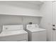 Laundry room with white appliances, white walls and shelves above the appliances at 10713 Noble Mesa Ave, Las Vegas, NV 89166