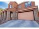 Exterior shot of a home showcasing a two-car garage and covered porch with stone pillars at 1125 Via Canale Dr, Henderson, NV 89011