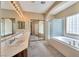 Bright bathroom featuring double sinks, a large mirror, a glass-enclosed shower, and a soaking tub at 129 Sapodilla Ln, Las Vegas, NV 89144