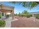 Charming backyard with covered patio area, mature trees, and minimalist desert landscaping at 2512 Desert Glen Dr, Las Vegas, NV 89134