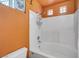 Bathroom with white tub and shower with orange walls and trim at 2707 Commitment Ct, North Las Vegas, NV 89031