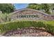 Community entrance with a stone 'COBBLESTONE' sign, manicured bushes, and colorful flowers at 2714 Cricket Hollow Ct, Henderson, NV 89074