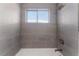 Close-up of bathtub and shower area with gray tiling and a window at 2825 Hickey Ave, North Las Vegas, NV 89030