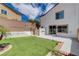 Charming backyard showcasing artificial grass, patio space, and a view of the home's facade at 3365 Moon Eclipse St, North Las Vegas, NV 89032
