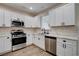 Bright kitchen featuring stainless steel appliances, white cabinets, quartz countertops, and modern flooring at 3365 Moon Eclipse St, North Las Vegas, NV 89032