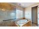 Well-lit bathroom featuring a soaking tub, glass-enclosed shower, and a glass block window at 3425 Fledgling Dr, North Las Vegas, NV 89084