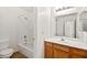 Bright bathroom featuring a tub with shower, white tiling and a wooden vanity with a large mirror at 4007 W Red Coach Ave, North Las Vegas, NV 89031