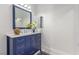 Well-lit bathroom featuring blue vanity with marble countertop, a decorative mirror, and stylish fixtures at 44 Tamarron Cliffs St, Las Vegas, NV 89148