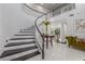 Bright, welcoming foyer featuring a curved staircase, table with flowers, and tiled flooring at 44 Tamarron Cliffs St, Las Vegas, NV 89148