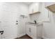 Clean laundry room with a modern sink, white cabinets, and door at 44 Tamarron Cliffs St, Las Vegas, NV 89148