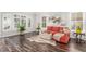 Inviting living room with a red sofa, hardwood floors, and bright natural light from large windows at 44 Tamarron Cliffs St, Las Vegas, NV 89148