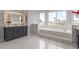 Luxurious main bathroom with a built-in tub, marble floors, and vanity with gray cabinets at 44 Tamarron Cliffs St, Las Vegas, NV 89148