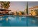 Serene pool area with a charming water feature, set beneath a covered patio and lush landscaping at 44 Tamarron Cliffs St, Las Vegas, NV 89148
