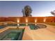 Backyard pool and spa area with accent lighting on brick wall, artificial turf and desert landscaping at 7125 Mountain Den Ave, Las Vegas, NV 89179