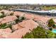 Aerial view of residential area with terracotta roofs, mature trees, pool, and the Las Vegas skyline in the distance at 7450 S Eastern Ave # 2073, Las Vegas, NV 89123