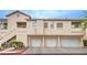 Exterior view of multi-Gathering unit with tan stucco, tile roof, garages and stairs to upper units at 7450 S Eastern Ave # 2073, Las Vegas, NV 89123