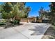 Spacious driveway leading to a three-car garage, with mature trees and partial landscaping at 7504 Via Sistina St, Las Vegas, NV 89131