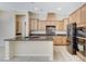 Spacious kitchen features an island with a sink, wood cabinets, and stainless steel appliances at 7504 Via Sistina St, Las Vegas, NV 89131