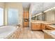 Bathroom featuring a soaking tub, glass block window, and vanity with marble countertops at 7520 Captains Harbor Dr, Las Vegas, NV 89117
