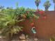 Exterior space showing lush greenery and vibrant orange flowers cascading down a textured wall, enhanced by garden art at 7526 Gossamer Wind St, Las Vegas, NV 89139