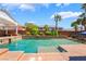 Incredible backyard pool with a covered patio, palm trees, lush green bushes, and sunny blue skies at 7526 Gossamer Wind St, Las Vegas, NV 89139