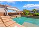A backyard pool with a covered patio, ample seating, and stairs leading into the water at 7526 Gossamer Wind St, Las Vegas, NV 89139