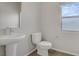 Bathroom featuring a sleek pedestal sink, modern toilet, and a window at 8016 Carpenter Creek Ave, Las Vegas, NV 89113