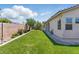The backyard offers lush green grass, a covered patio, and a block wall for privacy at 8114 Lapis Harbor Ave, Las Vegas, NV 89117