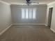 Bright bedroom with neutral walls, carpet flooring, and a ceiling fan with large windows and white shutters at 9232 Marlia St, Las Vegas, NV 89123