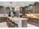A spacious kitchen featuring dark wood cabinets, a granite island, and stainless steel appliances at 961 Cutter St, Henderson, NV 89011
