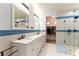 Bathroom with double sinks and white tiled shower with blue stripe accent at 9986 Sand Key St, Las Vegas, NV 89178