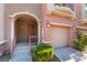 Inviting townhome entrance with a covered porch, landscaped shrubbery, and one-car garage at 9986 Sand Key St, Las Vegas, NV 89178
