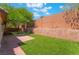 Manicured backyard featuring well-maintained lawn, tree, and block wall fencing at 10259 Wolves Den Ln, Las Vegas, NV 89178