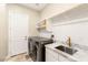 Well-organized laundry room with front loading washer/dryer, sink, counter space and white patterned tile backsplash at 1200 Dry Point Ct, Las Vegas, NV 89144