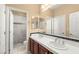 Well-lit bathroom with double vanity, a large mirror, and a tiled shower with glass doors at 17 Morninglow Pass, Henderson, NV 89052