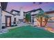 A large backyard featuring green grass, a fireplace, a stone trimmed facade and small palm trees at 2369 Green Mountain Ct, Las Vegas, NV 89135