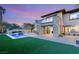 Backyard featuring pool, stone accents, manicured green grass, and a second story balcony at 2369 Green Mountain Ct, Las Vegas, NV 89135