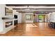 Living room features hardwood floors, exposed beam ceiling, fireplace, large window, and glass doors, blending indoor-outdoor living seamlessly at 2369 Green Mountain Ct, Las Vegas, NV 89135