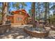 Backyard with a covered hot tub, dining and firepit areas surrounded by mature trees and professional landscaping at 274 Ski Trail Rd, Mount Charleston, NV 89124