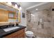 Bathroom with stone shower, granite countertops, log-framed mirror, and wood cabinets at 274 Ski Trail Rd, Mount Charleston, NV 89124
