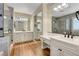 Bright bathroom featuring dual vanities with white cabinets, a glass shower, and a large mirror at 3618 Auckland Castle St, Las Vegas, NV 89135