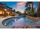 Beautiful pool with rock features and patio area in the backyard at sunset at 4200 Scott Peak Ct, Las Vegas, NV 89129