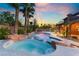 Beautiful backyard pool and patio area with rock features and lush palm trees at 4200 Scott Peak Ct, Las Vegas, NV 89129