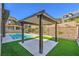 Outdoor pergola covering a tiled patio with artificial grass, ideal for relaxing and enjoying the backyard views with a pool nearby at 5429 Succulent Rose Dr, Las Vegas, NV 89135