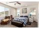 Bright bedroom featuring a ceiling fan, three windows, a comfortable chair, and a black ottoman with a floral comforter at 5633 Alitak Bay St, North Las Vegas, NV 89081