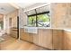 Well-lit kitchen featuring a farmhouse sink below a large window with stone wall accent at 5741 S Pearl St, Las Vegas, NV 89120