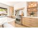 Well-lit kitchen with stone walls, wood cabinets, modern stainless-steel appliances, and open shelving at 5741 S Pearl St, Las Vegas, NV 89120