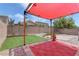 A well kept backyard featuring a large patio area with a red canopy and synthetic grass at 6236 Tierra Cove St, North Las Vegas, NV 89081