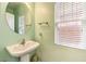 Charming powder room with a pedestal sink, round mirror and natural light from the window at 6554 Macdoogle St, Las Vegas, NV 89166