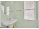 Cozy powder room features a pedestal sink, round mirror, and window for natural light at 6554 Macdoogle St, Las Vegas, NV 89166